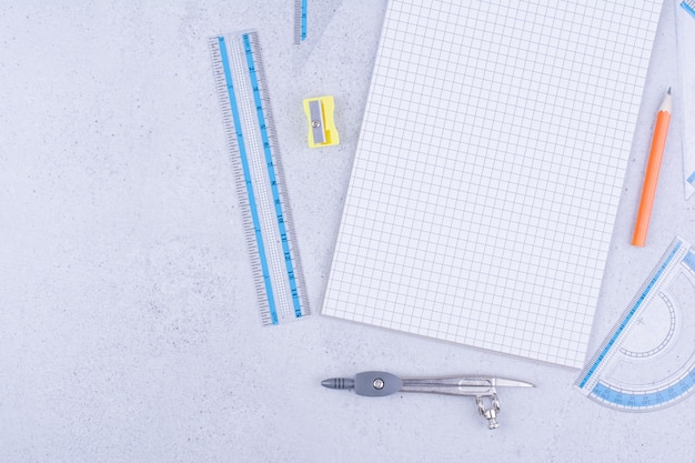 Un morceau de papier vierge avec un stylo, un crayon fusain, une règle et des séparateurs autour