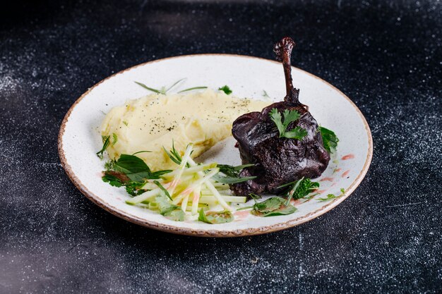 Un morceau de steak avec purée de pommes de terre et herbes vertes.