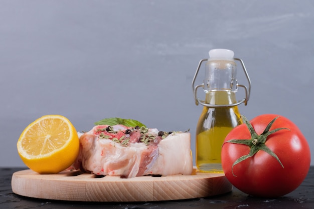 Morceau De Viande Crue Au Citron, Tomate Et Bouteille D'huile Sur Tableau Noir.