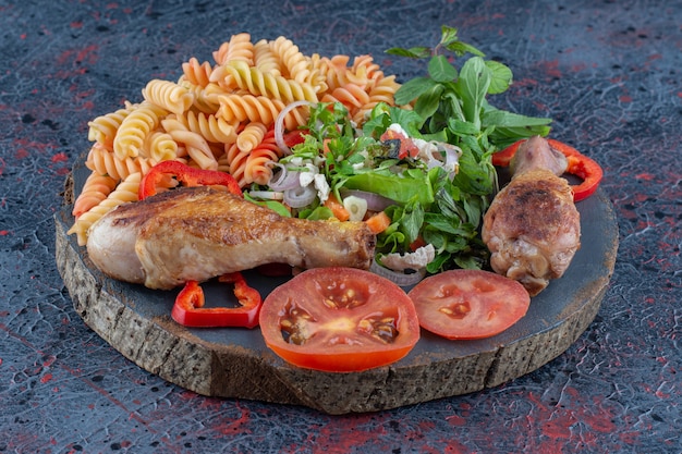 Un morceau de viande de cuisse de poulet frite en bois avec une salade de légumes.