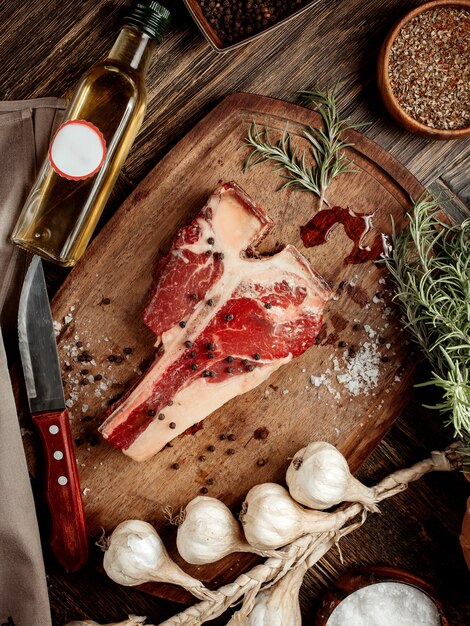 Un morceau de viande pour steak sur une planche de bois saupoudré d'épices