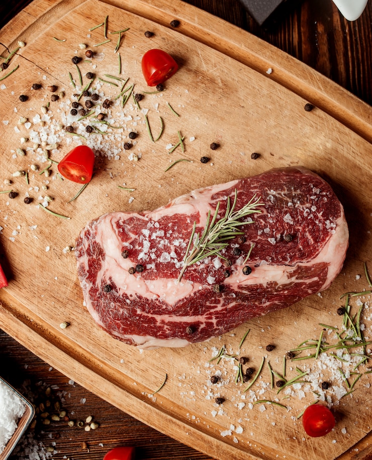 Photo gratuit un morceau de viande transformée avec des épices sur une planche de bois