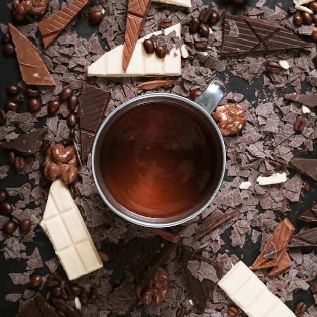 Photo gratuite morceaux de chocolat avec des grains de café torréfiés; noix et chocolat fondu dans une tasse