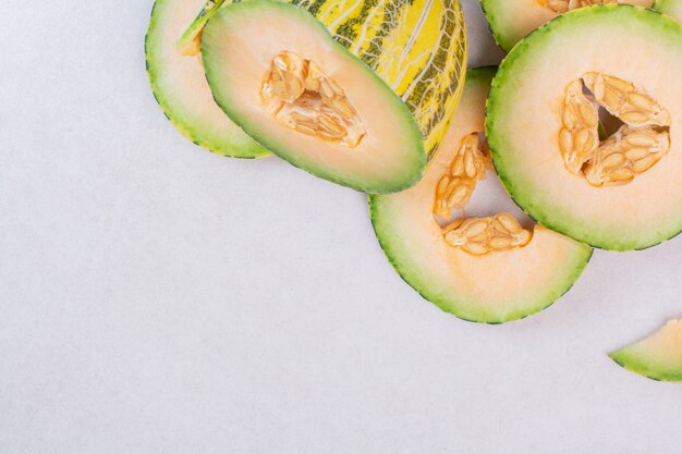 Morceaux de melon vert sur une surface blanche