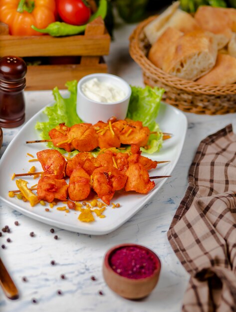 Morceaux de poitrine de poulet Sish Kebab, grillés et servis avec sauce à la crème, sumakh et laitue