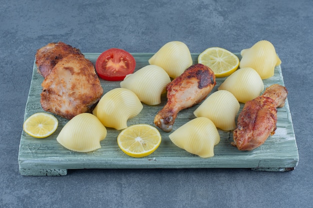 Morceaux de poulet grillés et pommes de terre bouillies sur planche de bois.