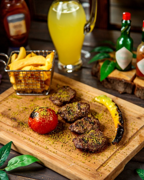 Morceaux de steak d'agneau servis avec frites tomates et poivrons grillés