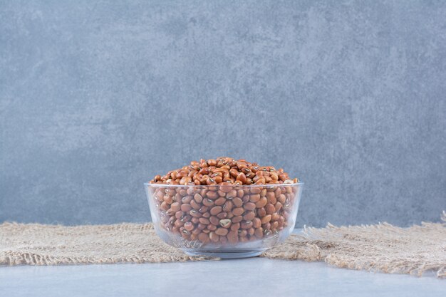 Morceaux de tissu à côté de haricot rouge entassés dans un bol en verre sur une surface en marbre