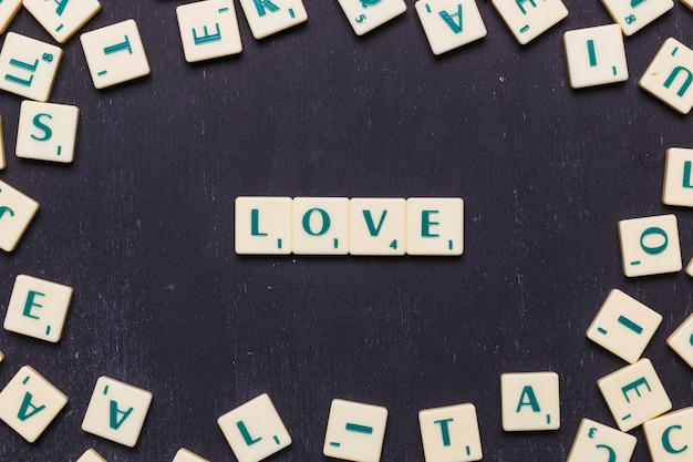 Mot d&#39;amour arrangé sur fond noir entouré de lettres de scrabble