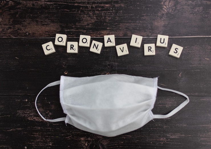 Photo gratuit mot «coronavirus» composé de blocs de scrabble et d'un masque facial sur une surface en bois