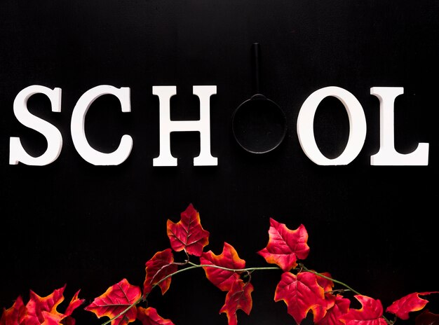 Mot de l'école blanche au-dessus de la branche de lierre rouge sur fond noir