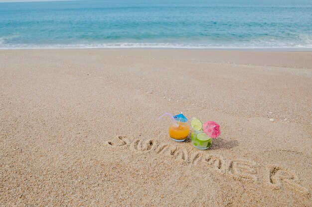 Mot écrit sur le sable et les cocktails