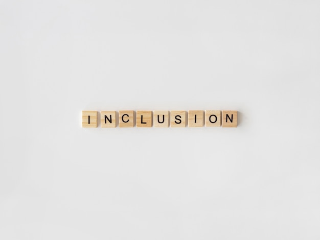 Photo gratuite mot d'inclusion écrit en lettres de scrabble sur fond blanc