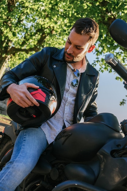 Motard espagnol cool avec une veste en cuir tout en tenant un casque