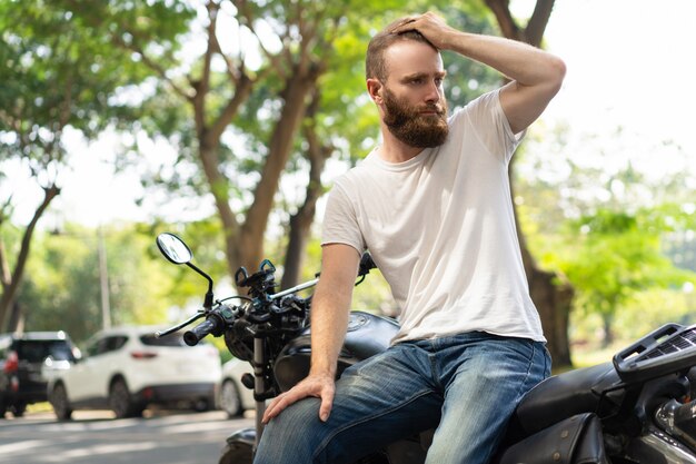 Motard sérieux s&#39;appuyant sur une moto cassée