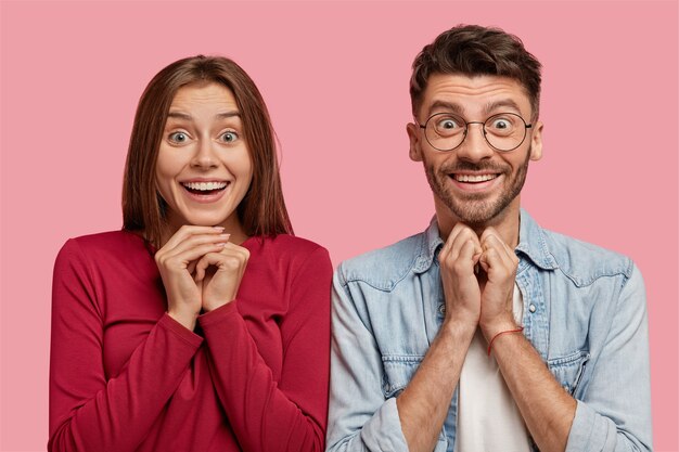 Émotif jeune couple posant contre le mur rose