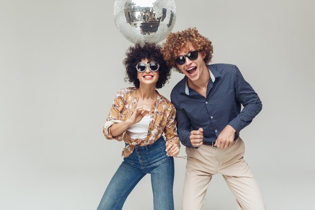 Émotionnel souriant couple d'amoureux rétro dansant près de boule disco.