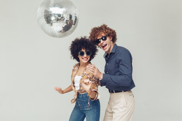 Émotionnel souriant couple d'amoureux rétro dansant près de boule disco.