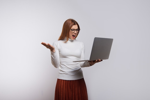 Émotionnelle femme tenant un ordinateur portable et hurlant