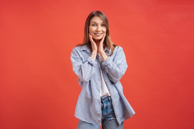 Émotions des gens - portrait de fille positive surprise sur mur rouge