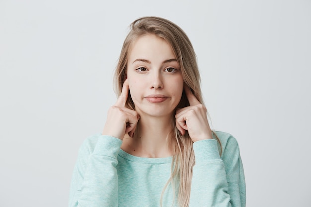 Émotions humaines négatives, réaction et attitude. Femme agacée frustrée avec des cheveux teints blonds se bouchant les oreilles avec les doigts, se sentant irrité par un bruit ennuyeux fort, ne peut pas se concentrer sur le travail