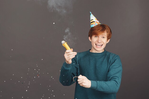 Émotions positives. Portrait de jeune homme aux cheveux roux en pull vert s'amuser sur la fête d'anniversaire avec la famille