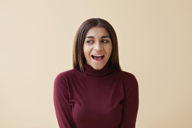 Émotions et sentiments humains positifs. Photo de jeune femme métisse émotionnelle à la recherche de côté avec une expression excitée, ouvrant largement la bouche