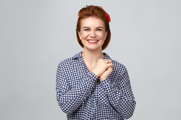 Émotions, sentiments et réactions. Portrait en studio de la belle jeune femme à pleines dents au gingembre faisant l'expression du visage heureux heureux, souriant largement, se réjouissant tout en recevant de bonnes nouvelles positives