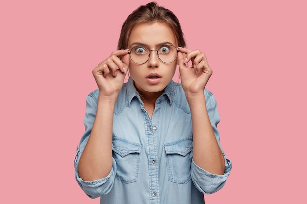 Émotive jeune femme de race blanche regarde si de grandes lunettes