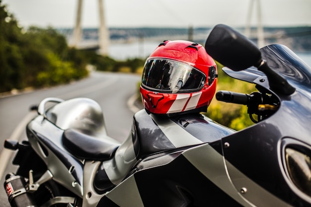 Une moto grise noire et un casque rouge.