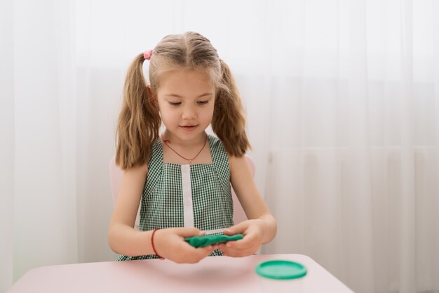 Moules de petite fille mignonne de pâte à modeler sur la table