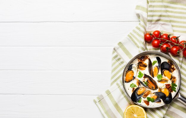 Moules plates en sauce blanche et côtés sur une nappe avec fond