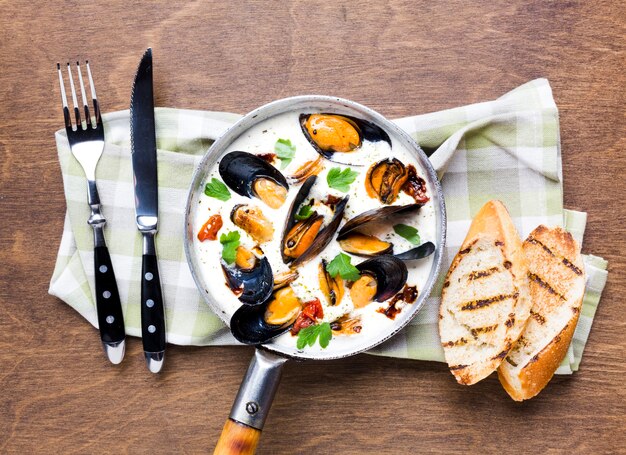 Moules plates en sauce blanche avec couverts sur nappe