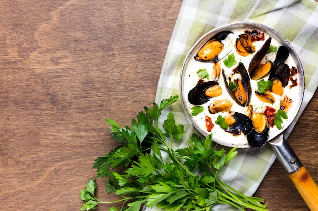 Photo gratuite moules plates en sauce blanche et persil sur une nappe avec fond