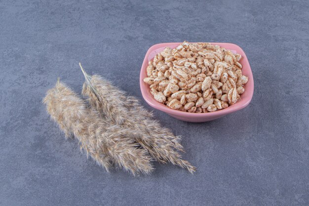 Muesli sucré dans un bol à côté de l'herbe de la pampa, sur fond bleu.