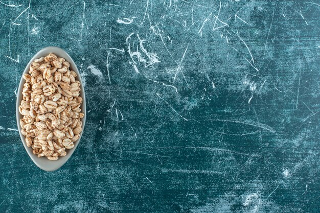 Muesli sucré dans un bol, sur la table bleue.