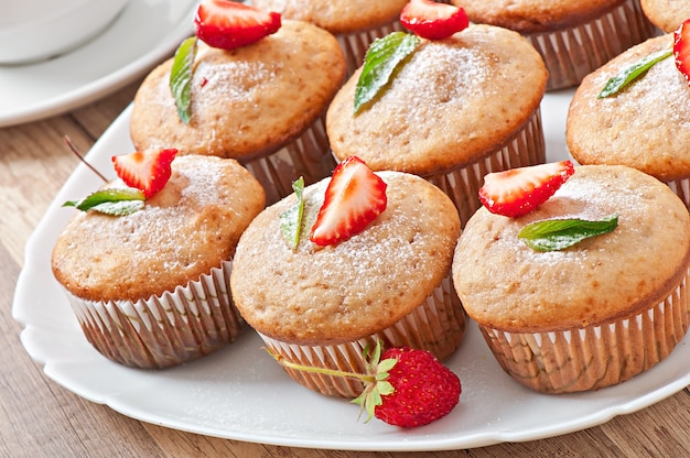 Muffin aux fraises sur une plaque blanche avec une fraise fraîche