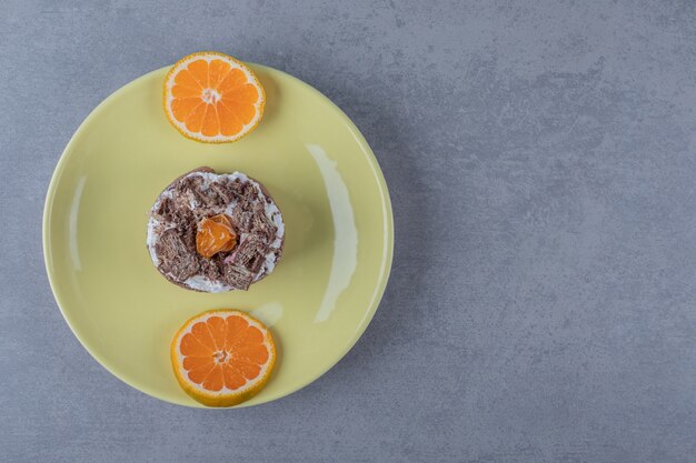 Photo gratuite muffin crémeux frais avec des tranches d'orange sur plaque jaune