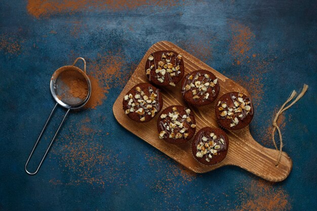 Muffins au chocolat et aux noix avec une tasse de café aux noix sur une surface sombre