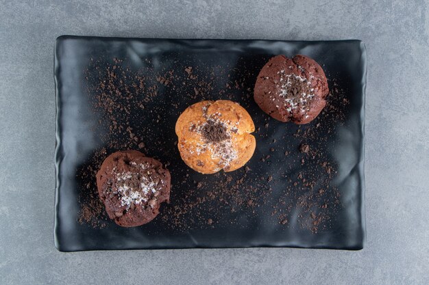 Photo gratuite muffins au chocolat avec muffin aux noix sur une planche noire