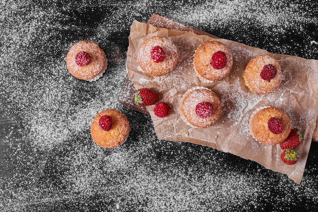 Muffins aux fruits rouges sur un plateau en bois.