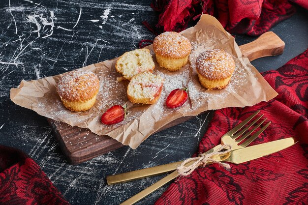 Muffins sur une planche de bois avec des couverts autour.