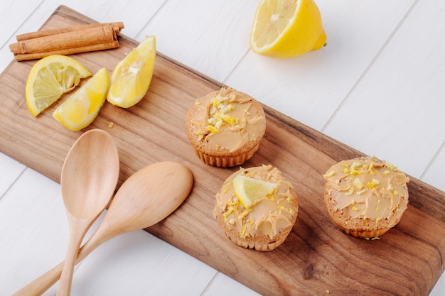 Muffins vue latérale avec citron et cannelle sur une planche avec des cuillères en bois