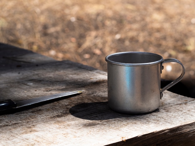 Mug et couteau vintage en métal sur une table en bois minable