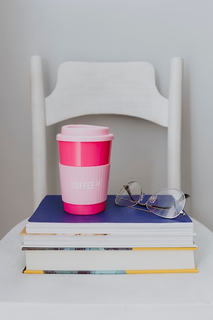 Photo gratuite mug de voyage rose sur une pile de manuels