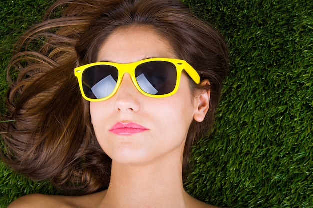 Photo gratuite mujer tumbada sobre la hiérarchie avec gafas de sol