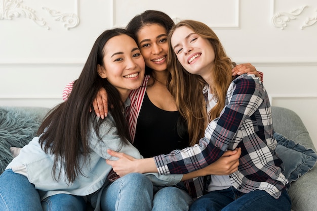 Multiethnic meilleures copines étreignant et assis sur un canapé