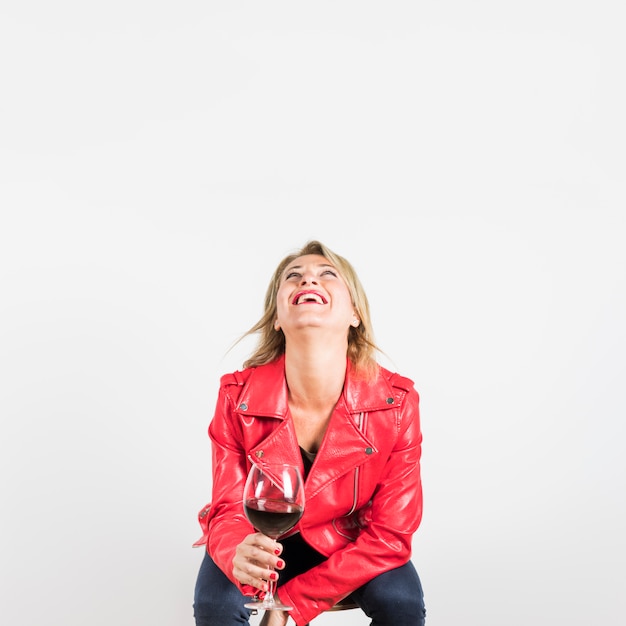 Mûr, femme, dans, veste rouge, tenue, verre vin, regarder, rire, contre, toile de fond blanc