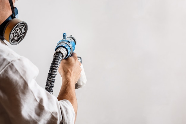 Mur de peinture travailleur avec pistolet de couleur blanche.