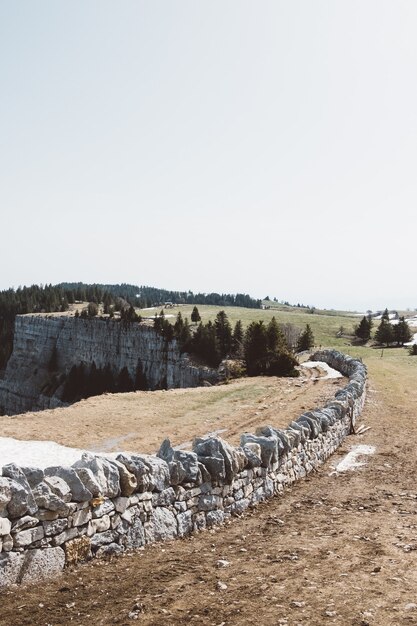 Mur de pierre près d'une falaise sur un champ vert sous un ciel nuageux